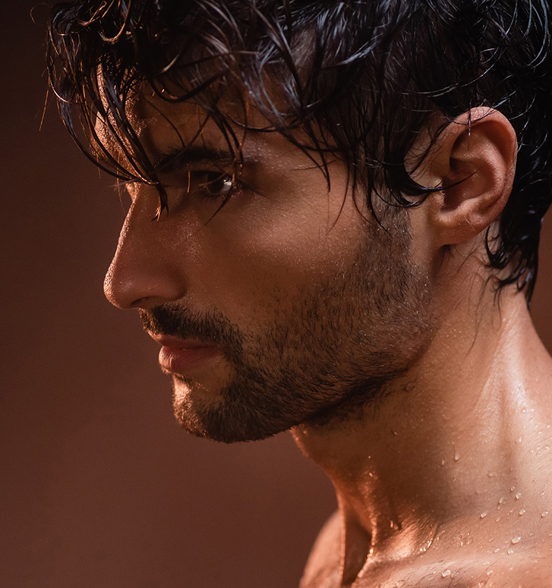 wet man looking away while posing on dark background
